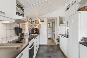 Cozinha moderna com armários brancos, bancada de aço inoxidável e forno embutido.