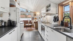 Eine moderne Küche mit weißen Schränken, einer schwarzen Arbeitsplatte und einem Fenster mit Blick auf einen Garten.