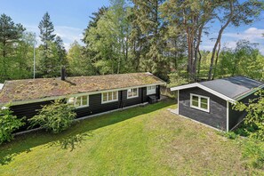 A cabin with a sloped roof, surrounded by trees and a grassy yard. - Danish summerhouse with Danish Holiday Atmosphere (Væggerløse)