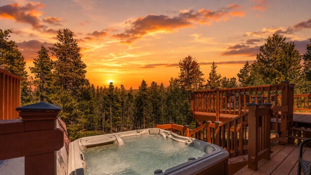 Un bain à remous sur une terrasse en bois, avec vue sur le coucher de soleil.