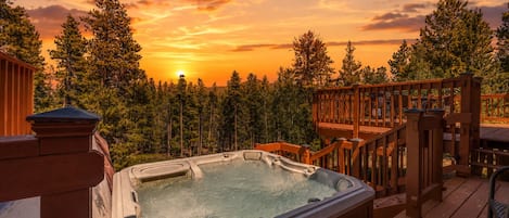 Jacuzzi en una terraza de madera con vista al atardecer.