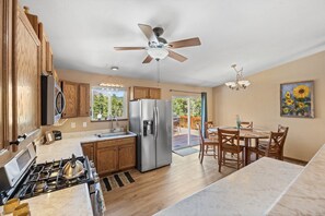 A kitchen with wooden cabinets, a stainless steel refrigerator, a gas stove, and a ceiling fan.