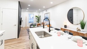 Una cucina moderna con una grande isola, mobili bianchi e uno specchio rotondo sopra il lavello.