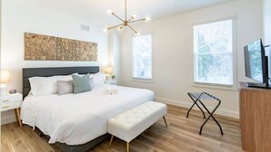 Una camera da letto con un letto, comodini, una panca, una TV e un originale lampadario.