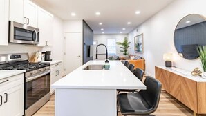 Una cucina moderna con isola centrale, elettrodomestici in acciaio inossidabile e zona pranzo con tavolo e sedie in legno.