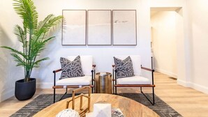 A modern living room with two chairs, a coffee table, and a large plant. - 2BR Home | Near T | Free Street Parking (Pittsburgh)