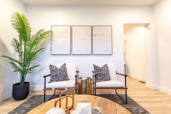 A modern living room with two chairs, a coffee table, and a large plant.