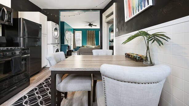 Une cuisine moderne avec un coin repas, comprenant un poêle noir, des armoires blanches et une table à manger avec des chaises.