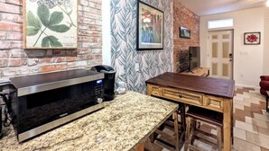 A kitchen with a microwave, a wooden table, and a patterned wall. - 1 Block from Butler St ★ Patio ★ Dog Friendly! (Pittsburgh)