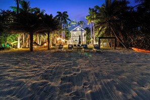 Ein Strandgrundstück mit einem großen Haus, Palmen und einer Hängematte.