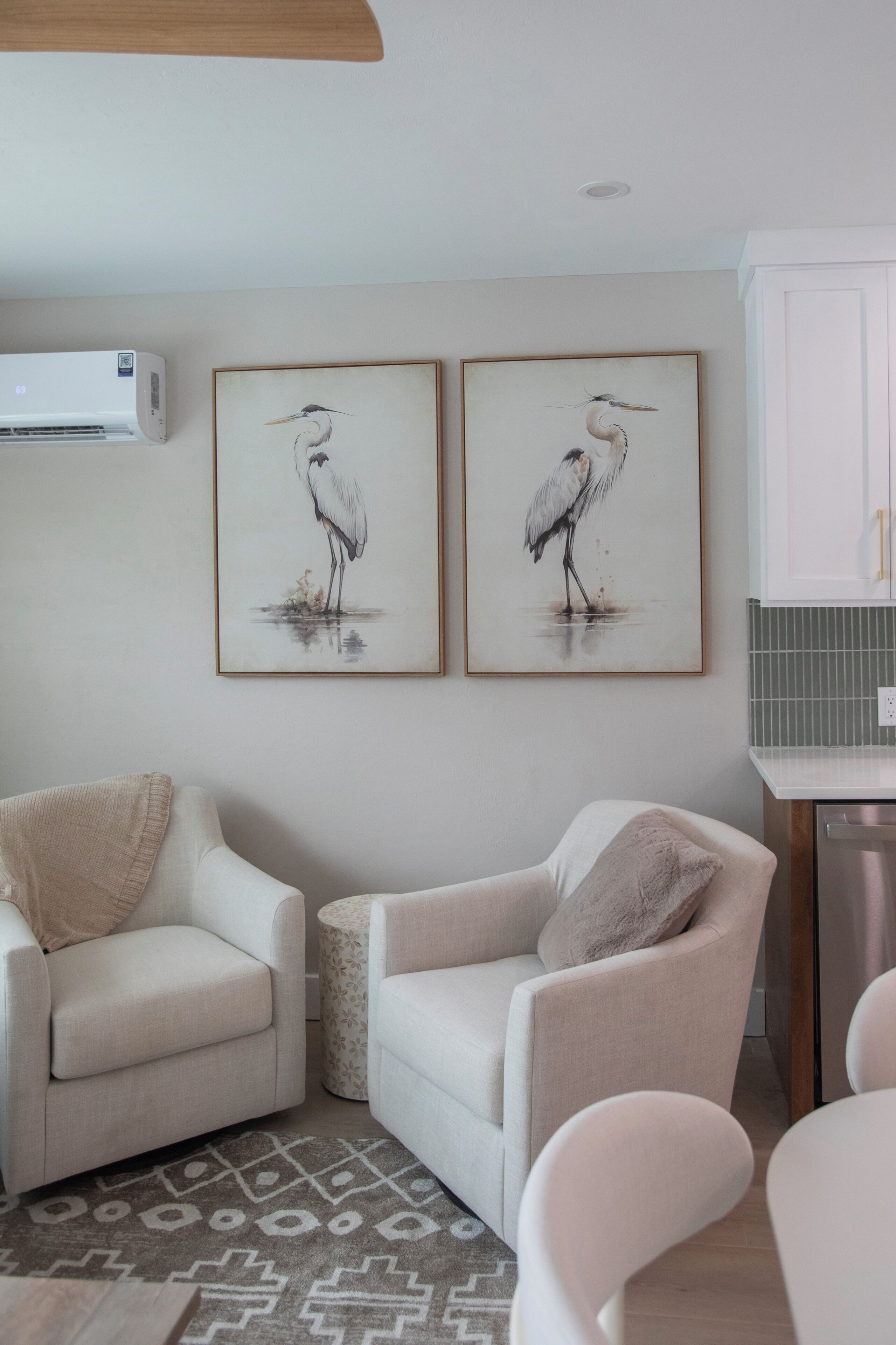 A living room with two armchairs, a small table, and a wall-mounted air conditioner.