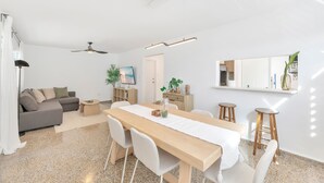 A modern living space with a dining area, a sofa, a ceiling fan, and a large mirror. - Santurce 3BR · Free Parking · Walk to Calle Cerra Bars (San Juan)