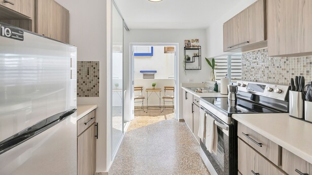 A modern kitchen with a refrigerator, stove, and dining area. - Santurce 3BR · Free Parking · Walk to Calle Cerra Bars (San Juan)