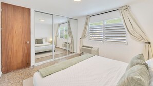 A bedroom with a bed, a wardrobe, a mirror, a window with curtains, and a radiator. - Santurce 3BR · Free Parking · Walk to Calle Cerra Bars (San Juan)