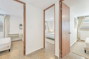 Ein Hotelzimmer mit Bett, Nachttisch, Spiegel und einem Fenster mit Vorhängen.