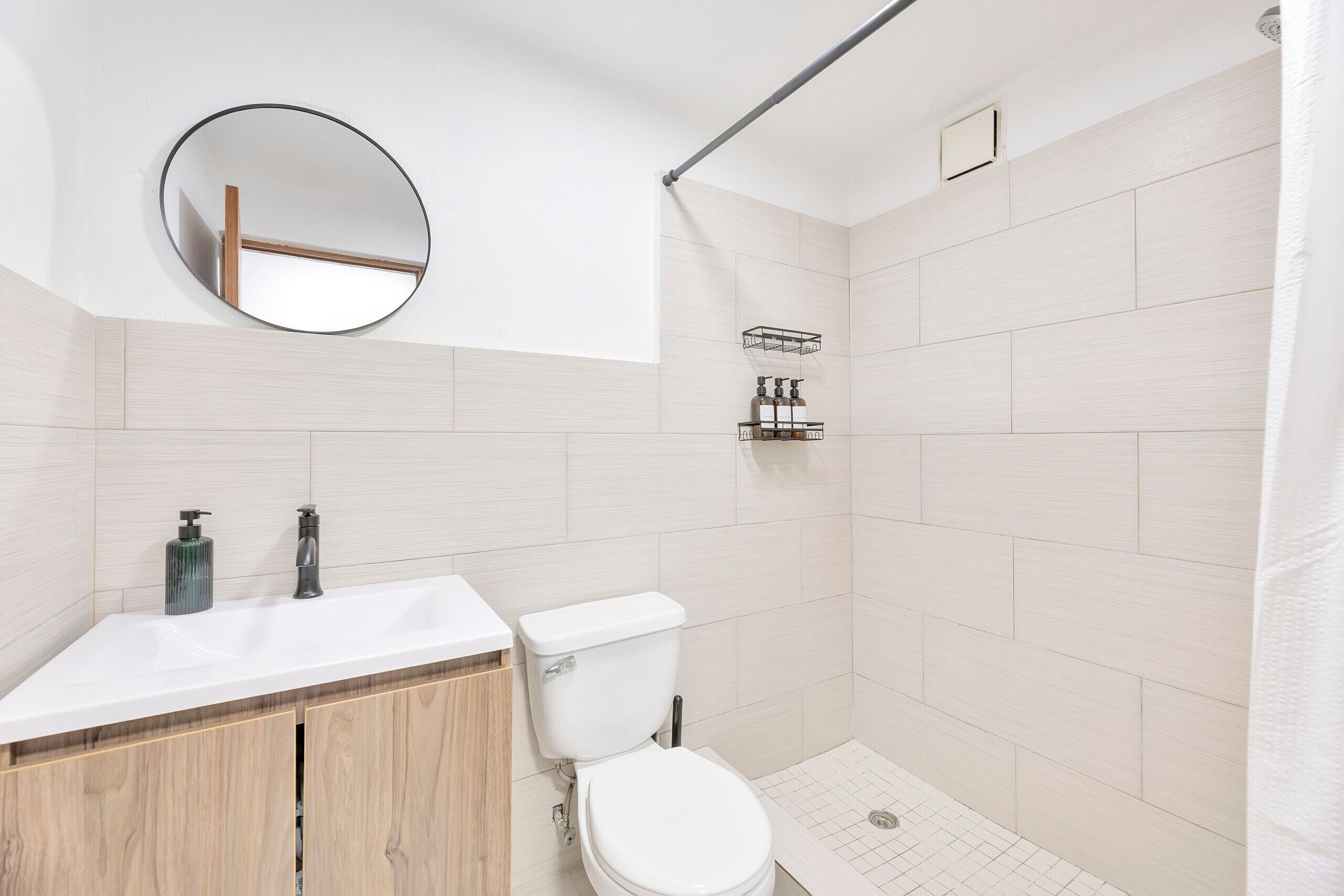 Un baño moderno con lavamanos, inodoro y ducha blancos.