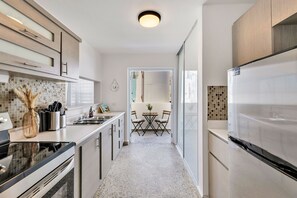 Eine moderne Küche mit Kochinsel, einem Kühlschrank und einer Essecke mit Tisch und Stühlen.