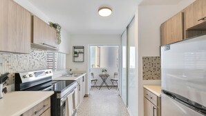 A modern kitchen with wooden cabinets, a stainless steel refrigerator, a built-in oven, and a tiled backsplash. - Calle Cerra Getaway 3BR w/ Balcony (San Juan)