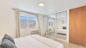 A bedroom with a bed, a window with blinds, a mirror, and a wardrobe. - Calle Cerra Getaway 3BR w/ Balcony (San Juan)