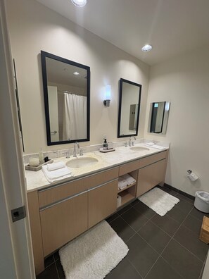 Un baño moderno con dos lavamanos, un espejo grande, un toallero y un dispensador de papel higiénico.