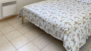 Une chambre à coucher avec un lit, un radiateur, une fenêtre et un tableau accroché au mur.