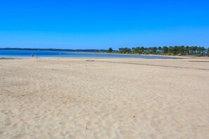 A beach with clear blue water, sandy shore, and trees in the background. - 245 - Your relaxing getaway in Hourtin - Near the lake and the ocean (HOURTIN)