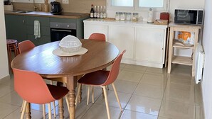 Une cuisine moderne avec une table à manger, des chaises, un four à micro-ondes et une fenêtre.