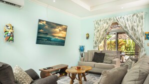 A living room with a sofa, a coffee table, and a painting of a seascape.