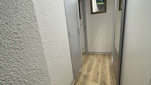 A hallway with a textured wall, wooden flooring, and a door leading to a room. - Seignosse océan, 2 bedroom apartment, walking distance to the beach, ideal for a family (SEIGNOSSE)