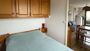 A bedroom with a bed, wooden cabinets, a small bedside table, and a red lamp. - Seignosse océan, 2 bedroom apartment, walking distance to the beach, ideal for a family (SEIGNOSSE)