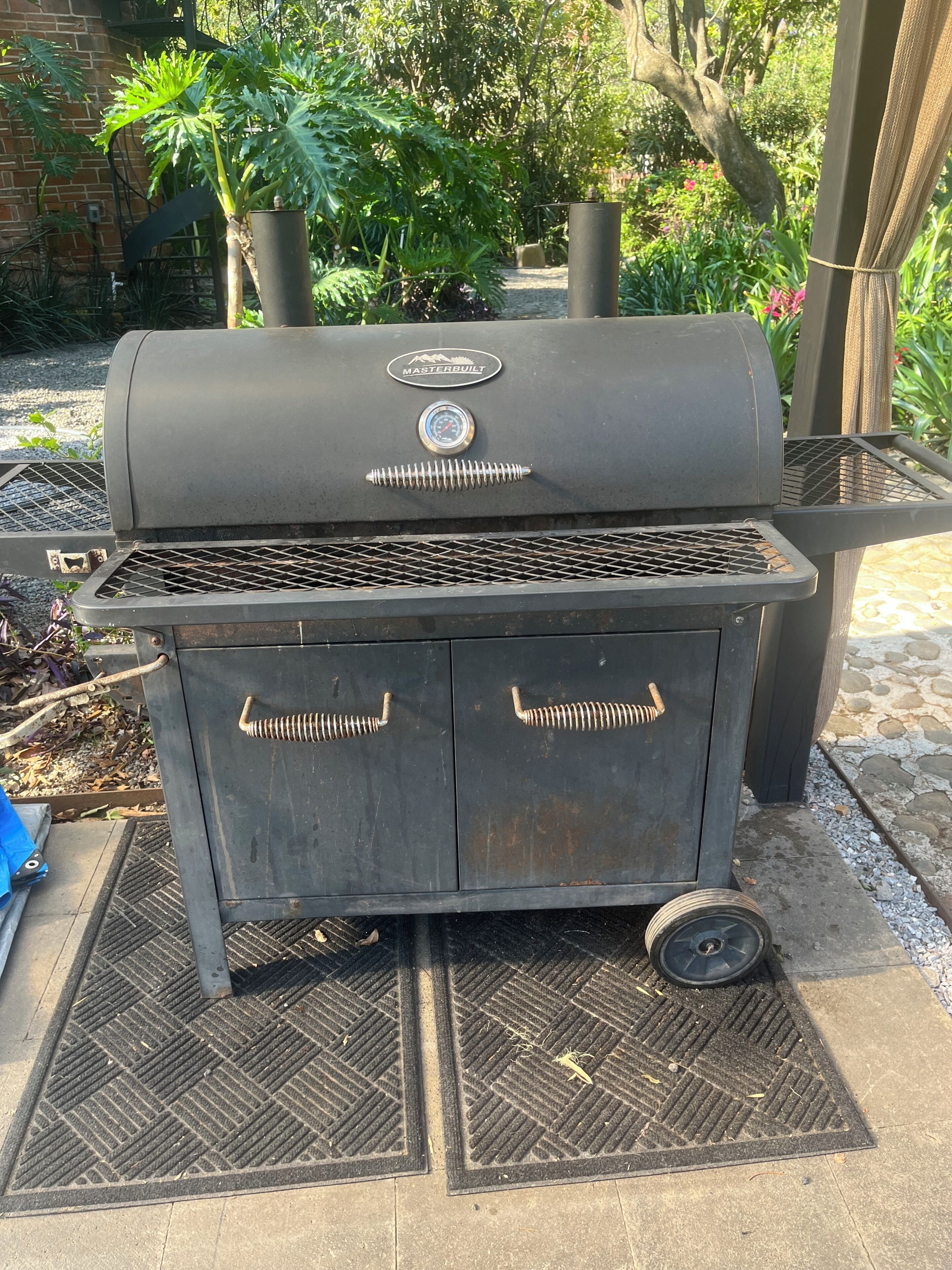 A portable barbecue grill with a digital thermometer, wheels, and a vented lid.