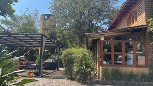 Un patio con una pérgola, un edificio de ladrillo con una ventana y un camino de piedra.