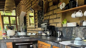 Una cocina con armarios de madera, microondas, cafetera y fregadero.