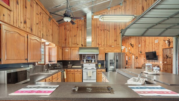 A kitchen with wooden cabinets, stainless steel appliances, and a central island with a tray. - Spacious 6-bedroom lodge in beautiful Damon with AC (Damon)