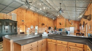 A kitchen with wooden cabinets, a large island, ceiling fans, and mounted animal heads. - Spacious 6-bedroom lodge in beautiful Damon with AC (Damon)