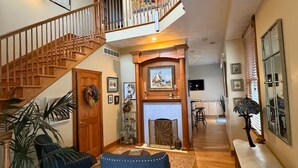 A spacious foyer with a wooden staircase, a fireplace, and a dining area. - Hilltop Haven in Mount Adams (Cincinnati)