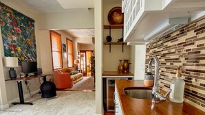 A modern kitchen with a wooden countertop, a sink, and a backsplash with tiles. - Hilltop Haven in Mount Adams (Cincinnati)