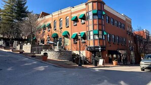 A multi-story building with a corner turret, large windows, and green awnings. - Hilltop Haven in Mount Adams (Cincinnati)