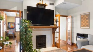 A living room with a fireplace, a flat-screen TV, and a sofa. - Hilltop Haven in Mount Adams (Cincinnati)