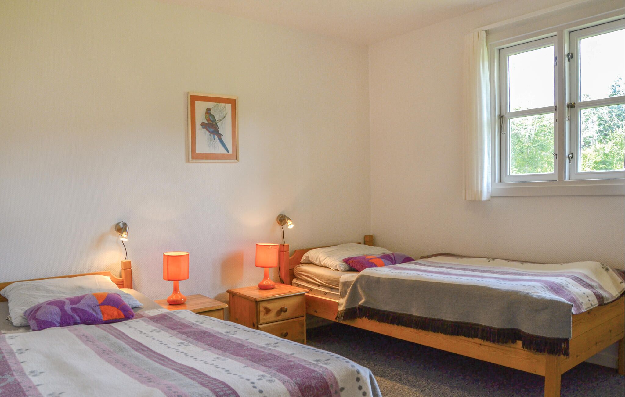 Un dormitorio con dos camas, una ventana y un cuadro colgado en la pared.