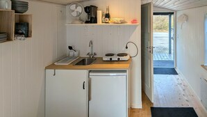 Ett kompakt kök med en diskho, ett litet kylskåp, en kaffebryggare och en fläkt.