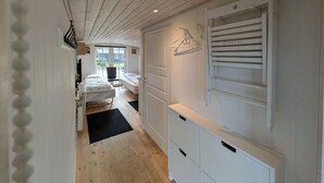En smal hall med trägolv, en säng, ett skrivbord och en garderob.