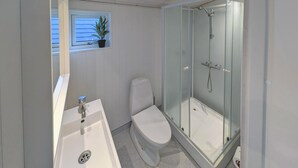 Ett badrum med toalett, handfat och en dusch med glasväggar.
