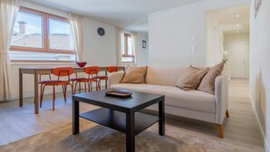 A living room with a sofa, a coffee table, and a dining area with chairs and a table. - The line Apartment in Zurich Oerlikon (Zurigo)