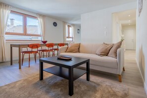 A living room with a sofa, a coffee table, and a dining area with chairs and a table. - The line Apartment in Zurich Oerlikon (Zurigo)