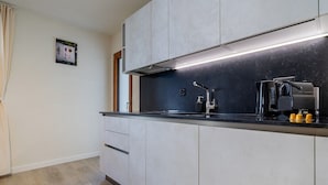 A modern kitchen with a black countertop, white cabinets, and a built-in range hood. - The line Apartment in Zurich Oerlikon (Zurigo)