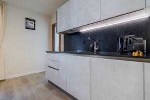 A modern kitchen with a black countertop, white cabinets, and a built-in range hood. - The line Apartment in Zurich Oerlikon (Zurigo)