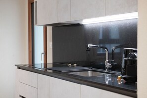 A modern kitchen with a black countertop, stainless steel sink, and a coffee maker.
