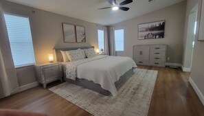 Ein Schlafzimmer mit einem Bett, Nachttischen, einer Kommode und einem Deckenventilator.