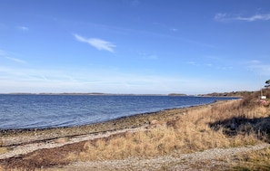 A coastal landscape with a clear sky, a rocky shoreline, and a distant view of land across the water. - Cozy home in Kirke Hyllinge with WiFi (Kirke Hyllinge)